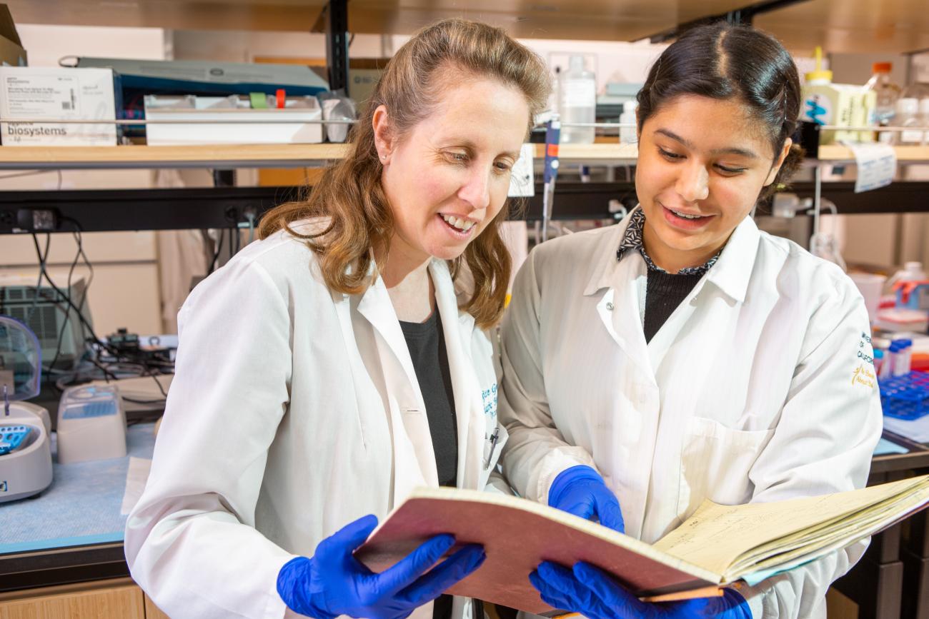Brigitte Gomperts and another researchers review a book of data in a UCLA lab.