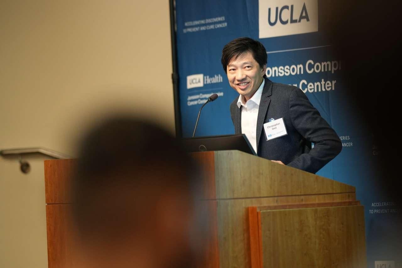 UCLA physician-scientist Christopher Seet smiles at a podium.