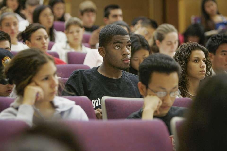 An undergraduate student listens attentively in a crowded lecture hall