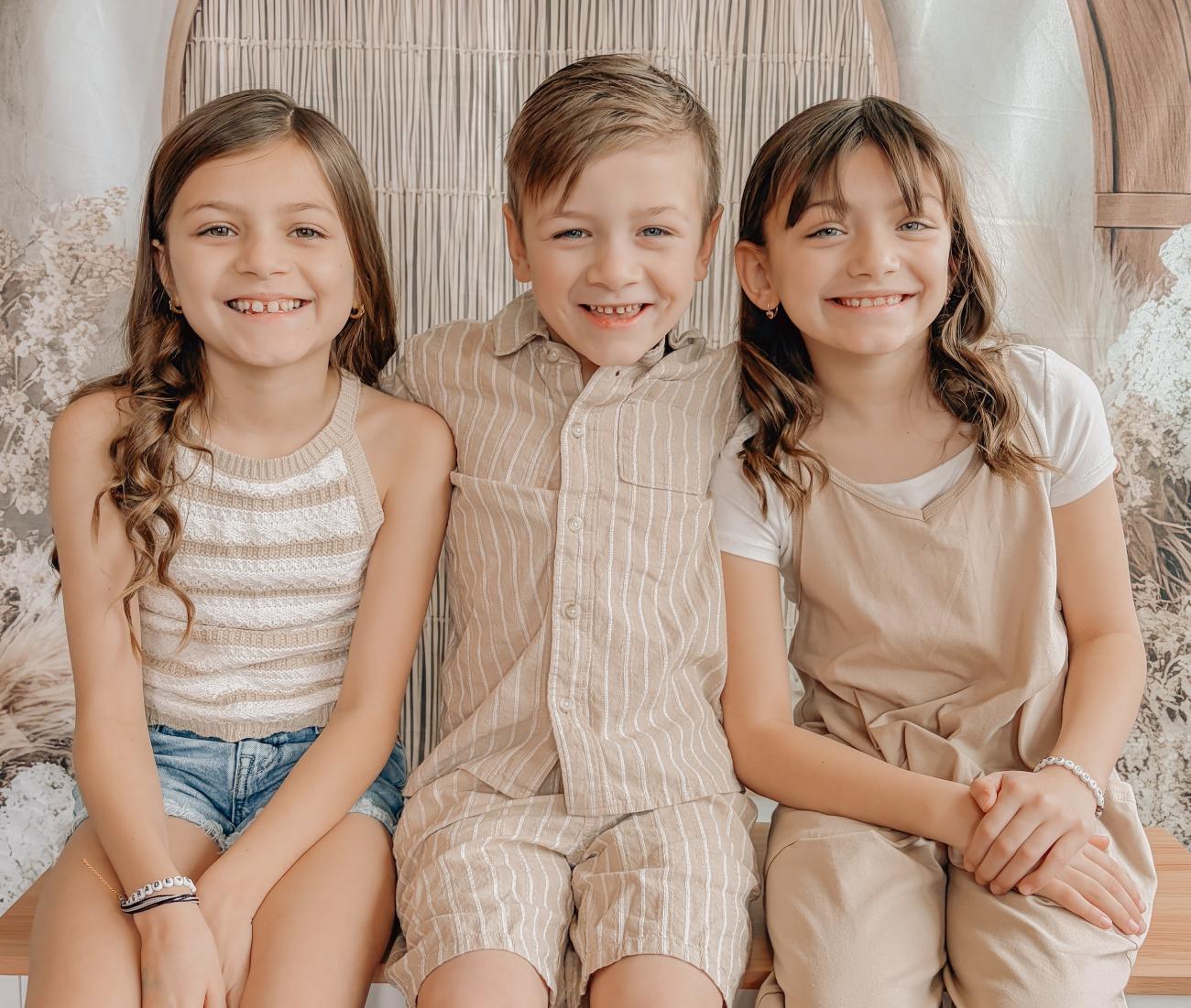 Siblings Ava, Landon and Olivia smile for a photo together.