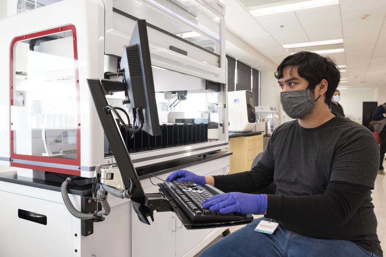 A man sits working before a screen in the COVID-19 SwabSeq lab.