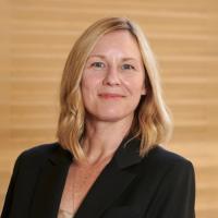 Amander Clark wears a dark blazer and smiles into the camera. 