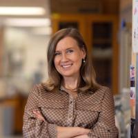 A researcher smiles into the camera inside a lab.