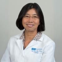 A doctor in a whitecoat smiles for a headshot.