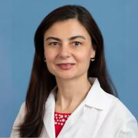 A woman in a labcoat smiles at the camera.