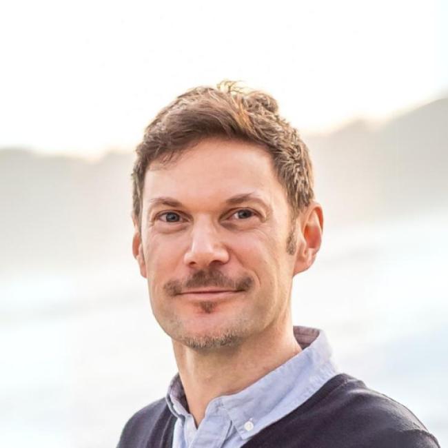 A smiling man photographed outdoors. 