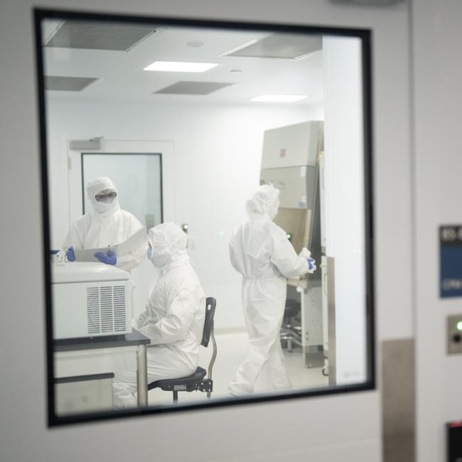 Three scientists clad in all-white "bunny" protective suits work inside the UCLA Center for Advanced Biotherapies.