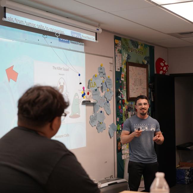trainee chris ochoa leading a high school outreach session in front of a classroom