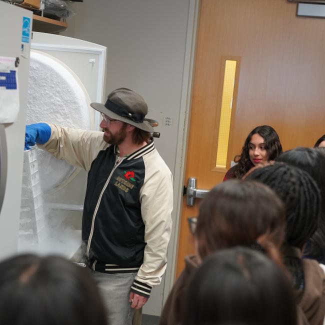trainee dylan smock pulling stem cells out of a freezer as high school students look on