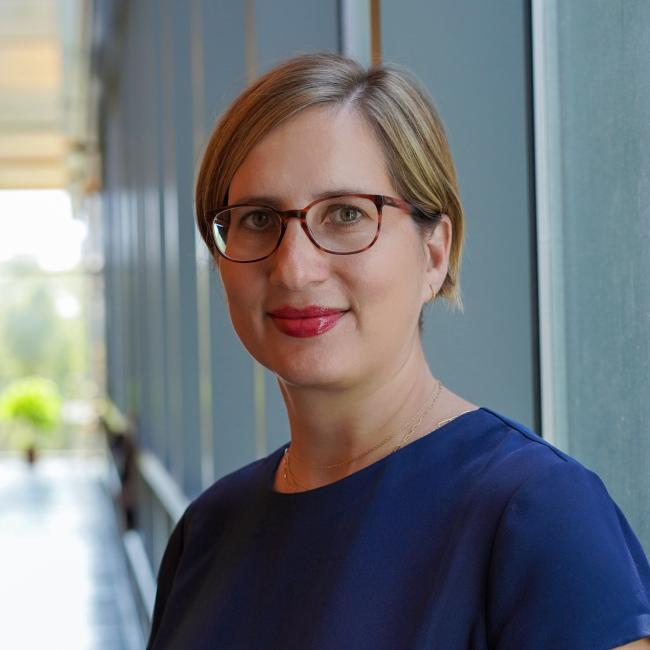 Female Admin with short blonde hair wearing a dark blue shirt. 