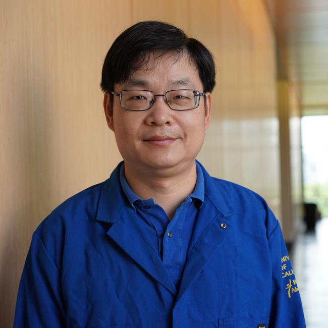 Male researcher with dark hair wearing a blue jacket.