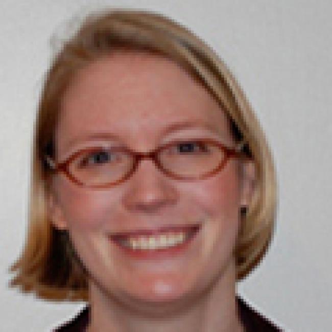 Headshot of Anne Lindgren, a woman with short blonde hair and glasses, smiling indoors.