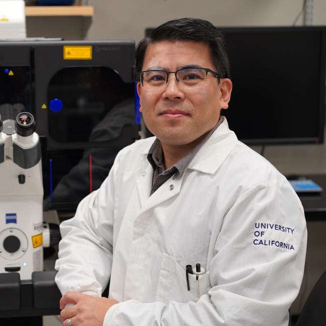 Ken Yamauchi standing next to microscope