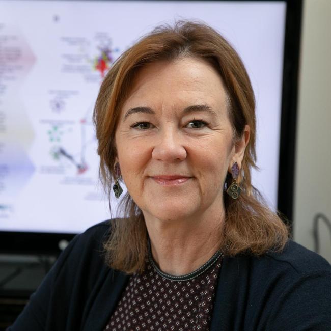 headshot of gay crooks wearing a printed top and black cardigan