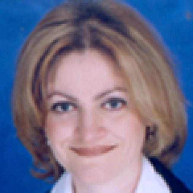 Headshot of Gayane Ambartsumyan, a woman with short blonde hair, smiling against a blue background.