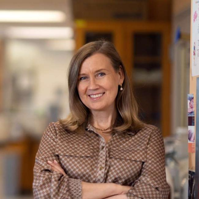 A researcher smiles into the camera inside a lab.