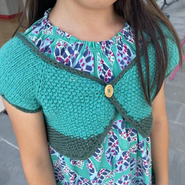 young girl wearing a green and blue knit shawl