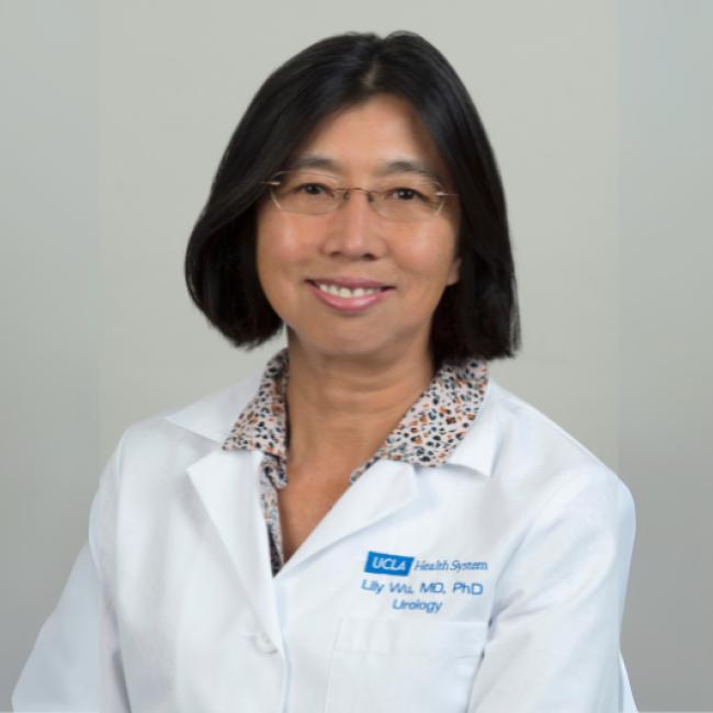 A doctor in a whitecoat smiles for a headshot.