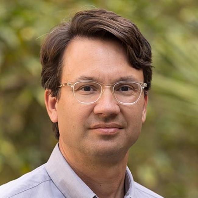 UCLA researcher Dr. William Lowry wears clear framed glasses in this headshot taken outdoors.
