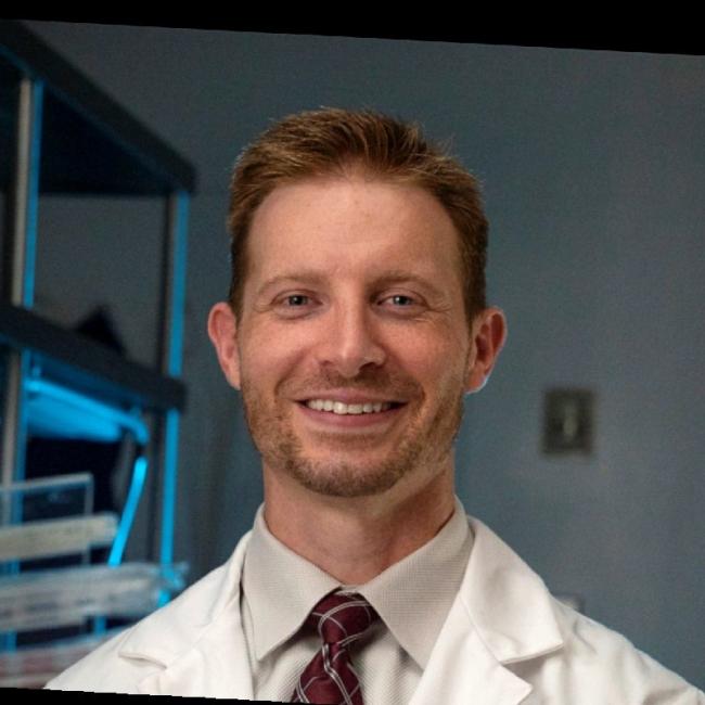 Sasine, Joshua smiles in a lab. 