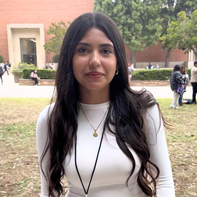high school girl with long hair and wearing a long sleeved white shirt standing on the UCLA campus