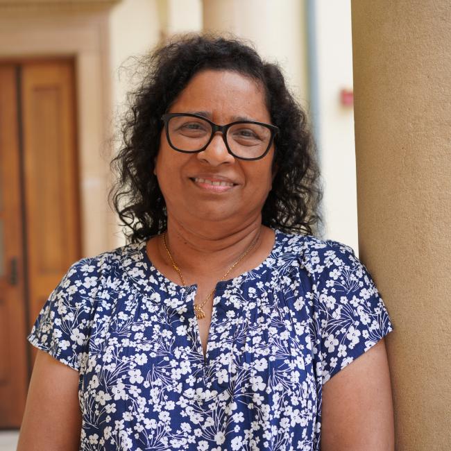 Female researcher with dark hair wearing a blue patterned shirt. 