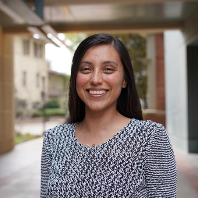 Female researcher with long dark hair in a black and white shirt. 